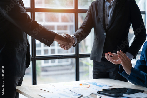 Two young Asian businessmen shaking hands and agreeing to invest in a real estate joint venture at the office.