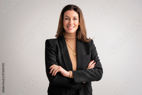 Confident mid aged woman wearing black blazer and standing at isolated background