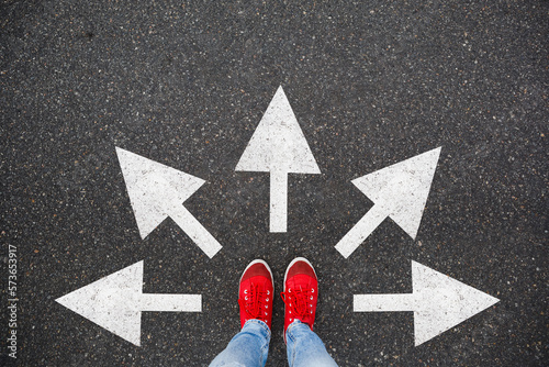 Feet walking away with many directions arrow. Taking decisions for the future sneaker shoes top view road. Selfie student child standing on floor or pathway to success. Creative idea, future concept