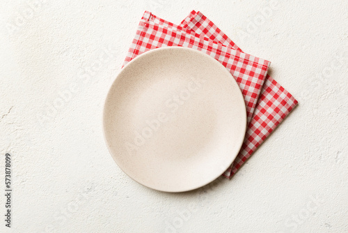 Top view on colored background empty round white plate on tablecloth for food. Empty dish on napkin with space for your design
