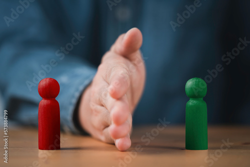 Palm hand blocking and divide between red and green wooden figure for resolving conflict and mediate management concept.