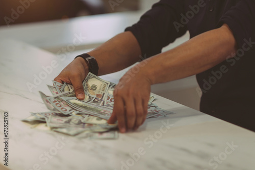 asian business male worker collect money. office treasurer showing arrange cash for company paycheck. spreaded money sheet paper got count by professional success treasurer of business bank on desk