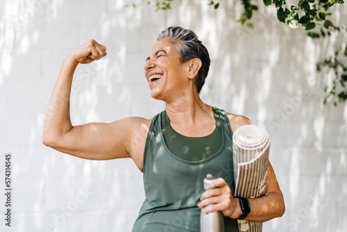 Elderly woman celebrates her fitness achievements by flaunting her bicep outdoors