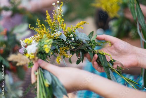 Making a Festive flower wreath, circlet of flowers, festival coronet of flowers on a bright sunny afternoon. Preparing for Midsummer night fest, or bachelorette party idea. How to Make a Flower Crown