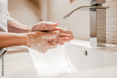 Girl washing hands with soap in bathroom