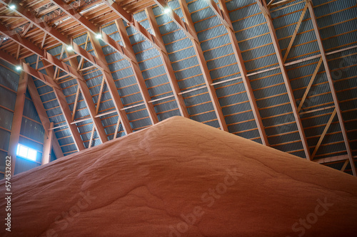 Pouring red phosphate fertilizers on pile in storehouse