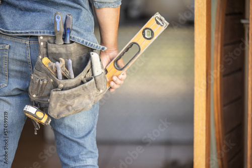 Maintenance man, bag and tools with hands, front door and home improvement service in property industry. Construction worker, back and jeans for working at house, building or real estate development
