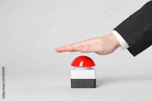 Man pressing red button of nuclear weapon on light gray background, closeup with space for text. War concept