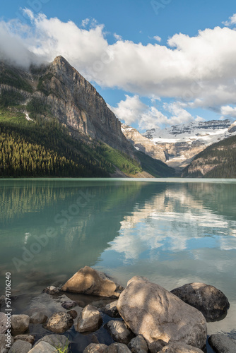 Vertikal view on Lake Louise with bolders in the foreground and snowy mountains with glacier in the background, Lake Louise, Alberta, Canada