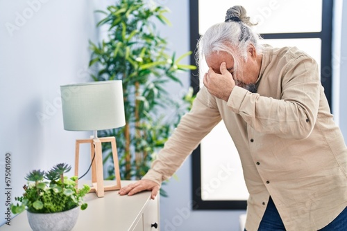 Middle age grey-haired man suffering dizzy standing at home