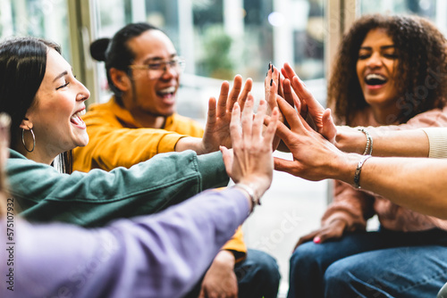 Multiracial happy young people stacking hands-Group of diverse friends having fun unity together indoors at table of community-Human resources Concept Creative and Relationship Youth Culture 