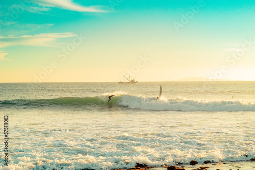 surfer on baja california beach with boat in the background