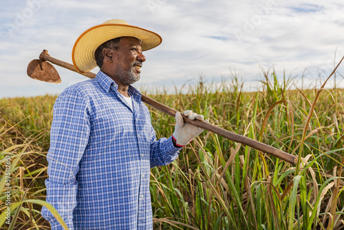 Black farmer smiling, with a hoe in his hands. Brazilian farmer. Family farming. Sugar cane. Closed plan. 
