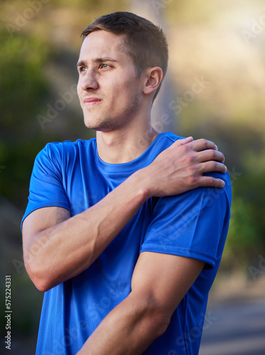 Injury, sport and man holding an arm with pain during running, exercise and strain from cardio. Health, accident and athlete runner with an injured muscle, painful body and inflammation in nature