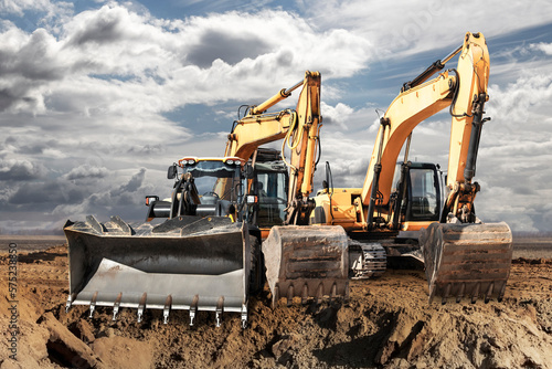 Bulldozer or loader moves the earth at the construction site against the blue sky. An earthmoving machine is leveling the site. Construction heavy equipment for earthworks.