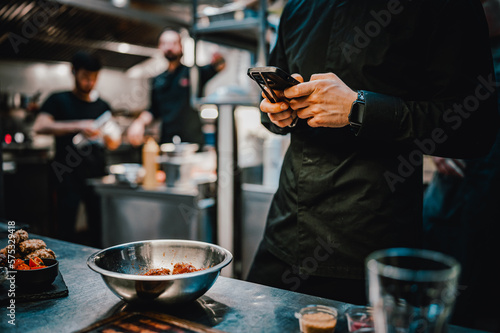 chef with phone in hands on restaurant kitchen