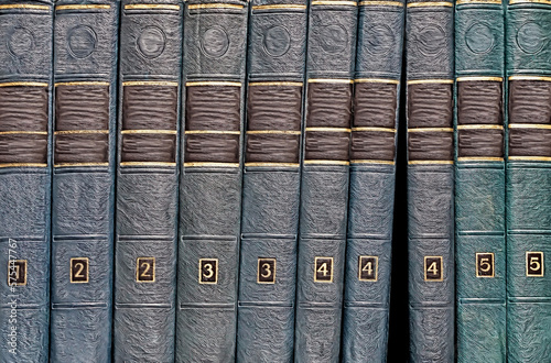 Encyclopedia in five volumes stacked vertically on the bookshelves, photo illustration