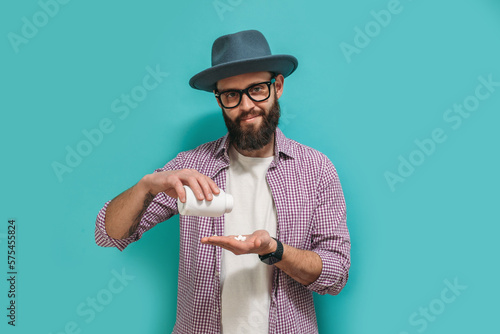 A man with a beard pours pills from a jar onto his hand. The concept of taking pills. Erection pills, vitamins, dietary supplements