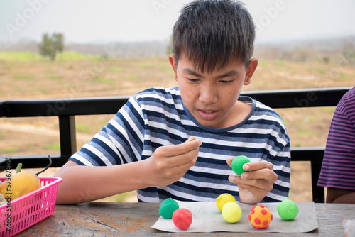 Asian boy spending free time with modeling clays at home by sculpting plasticine into the shapes of animals, fruits and other things at home, soft and selective focus, copy space.