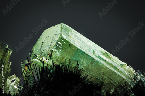 green beryl (emerald) on schorl (black tourmaline) matrix. macro detail texture background. close-up raw rough unpolished semi-precious gemstone with black background