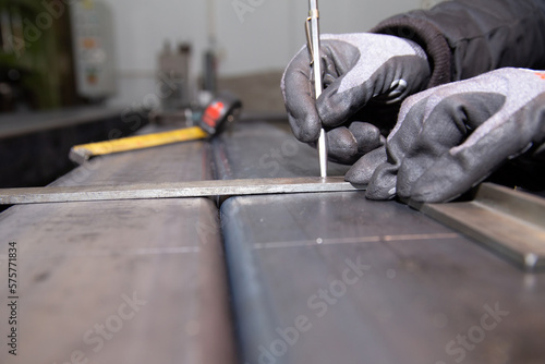 The worker makes a mark on a metal surface. Drilling holes in metal profiles for mounting metal structures. Construction.