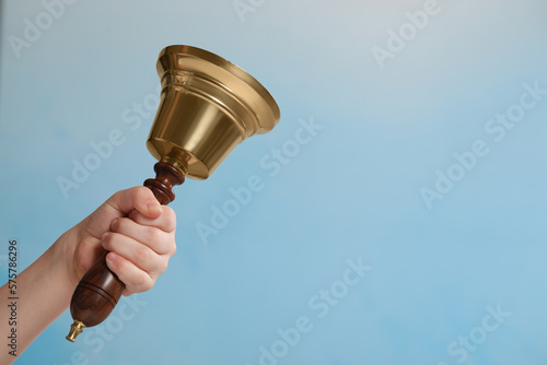 Pupil with school bell on light blue background, closeup. Space for text