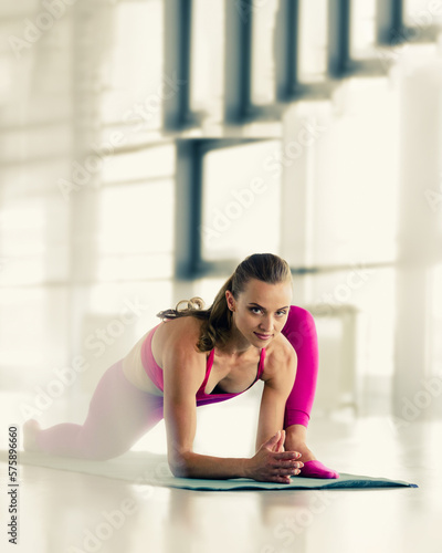Young fit healthy woman doing stretching exercises on mat in gym