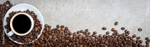 Filiżanka kawy z kawowymi fasolami na popielatym kamiennym tle. Widok z góry
