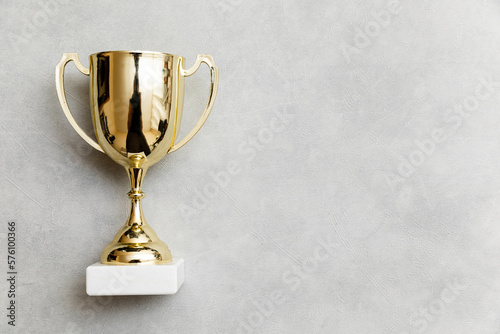 Simply flat lay design winner or champion gold trophy cup on concrete stone grey background. Victory first place of competition. Winning or success concept. Top view copy space