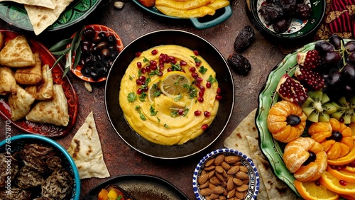 Hummus is a Middle Eastern savory dish made from cooked, mashed chickpeas blended with tahini, lemon juice, pomegranate berries and garlic. Authentic culinary composition in traditional dishes