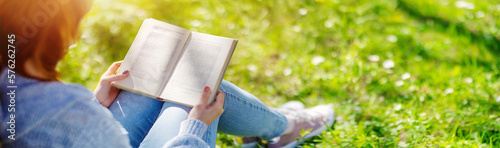 Woman sitting on the blossoming meadow with book in her hands.