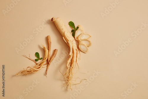 Korean ginseng root and some ginseng slices decorated on beige background. Blank space for text or product adding