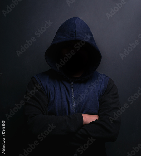 Danger lurks within the dark. Portrait of an unrecognisable hooded man posing against a dark background.