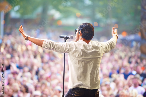 Charismatic frontman. A singer performing on stage at an outdoor music festival.