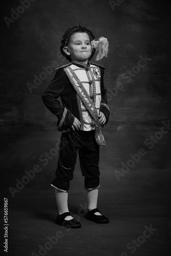 Black and white portrait of little boy dressed up as medieval character, little prince and pageboy. Retro fashion, emotions, theater art concept