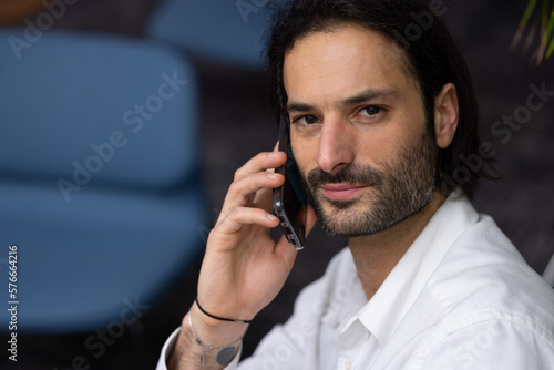 portrait d'un jeune homme d'affaires ou employé de bureau qui travaille sur son ordinateur portable dans un bureau confortable et qui communique avec son téléphone portable