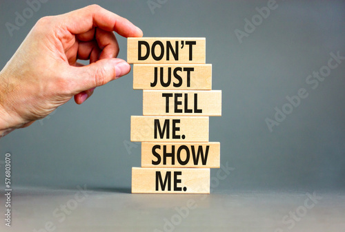 Tell or show symbol. Concept words Do not just tell me, show me on wooden blocks. Beautiful grey table grey background. Businessman hand. Business tell or show concept. Copy space.