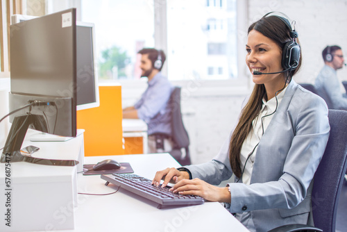 Smiling woman operator agent with headset responding to client's messages during online chat at customer support department. Online support, call center, helpdesk concept.