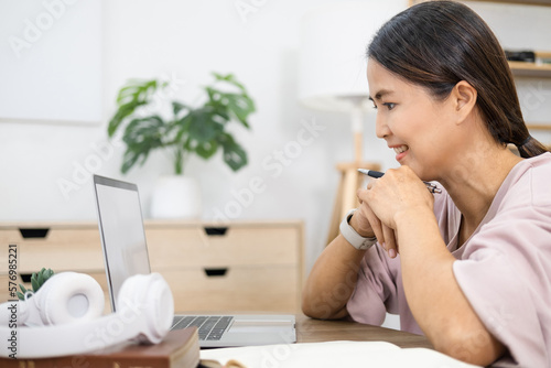 Happy asian woman in online learning , enjoying watching educational webinar on laptop. Smiling young businesswoman holding video call with clients partners.Young female student study in home.