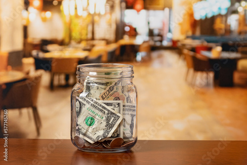 Tip jar in restaurant dining room. Service industry tipping, minimum wage and gratuity concept.