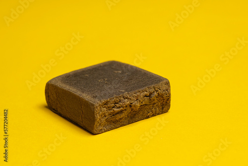 Hashish stick ready for sale on a yellow background. Medical marijuana extraction dry hashish cannabis pollen.