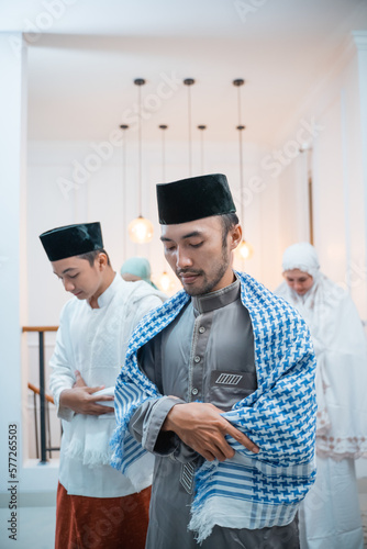 Asian men in caps perform iftitah prayer movements during congregational prayers