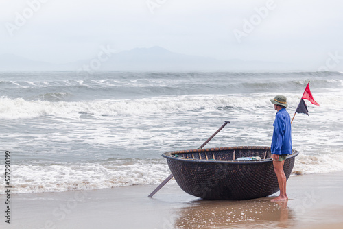 Pêcheur et sa barque traditionnelle en coquille qui attend devant la mer