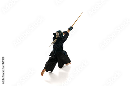 Top view. Man, professional kendo athlete in uniform with helmet training with bamboo shinai sword against white studio background. Concept of martial arts, sport, Japanese culture, action and motion