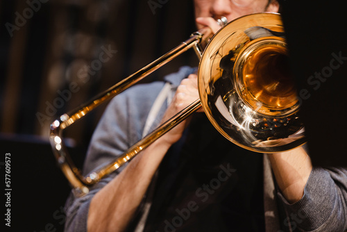 A musician playing a trombone during a casual wind ensemble rehearsal just before the concert