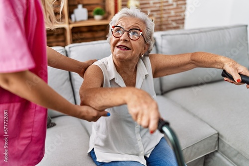 Senior grey-haired woman patient supported for nurse and walker at geriatric