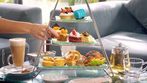 Woman hand take slice of cake from a towering display of afternoon tea