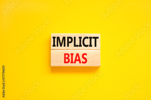 Implicit bias symbol. Concept words Implicit bias on wooden block. Beautiful yellow table yellow background. Business psychology implicit bias concept. Copy space.