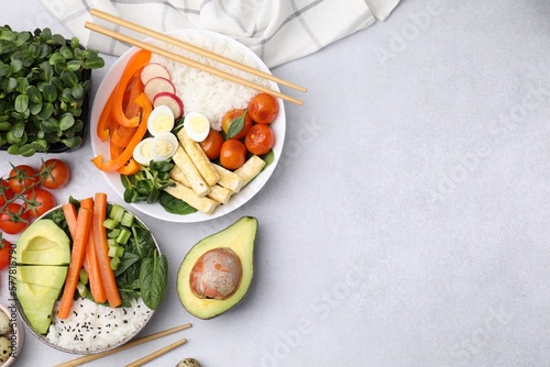 Delicious poke bowl and ingredients on light grey background, flat lay. Space for text