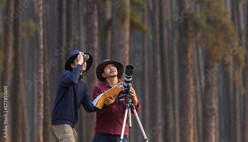 Team of the Asian naturalist looking at the new discovering bird species while exploring in the pine forest for surveying and locating the rare biological diversity and ecologist on the field study